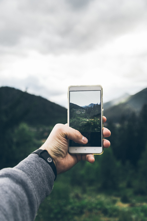 man taking picture of the mountains on his phoneの写真素材