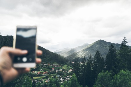 man taking picture of the mountains on his phoneの写真素材