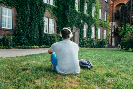 man sitting on the ground in city park and looking on old buildingの写真素材