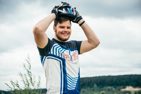 man near standing near lake with bicycle and check helmetの写真素材