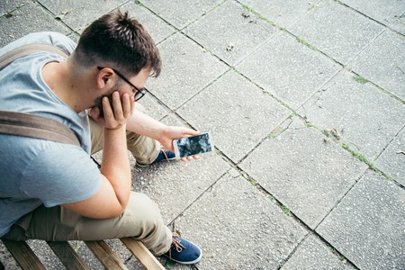 man holding smartphone with cracked screenの写真素材