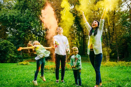cute european family plaing with holi paints in the parkの写真素材