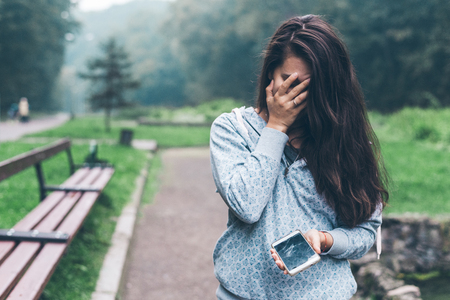 woman standing in the park with cracked phoneの写真素材