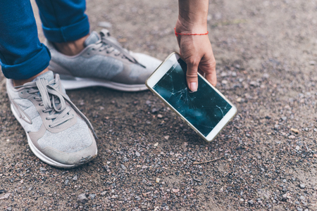 woman dropped mobile phone on the ground and smashed the screenの写真素材