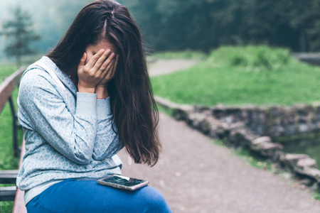 woman sitting on the bench with cracked phone