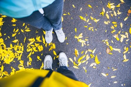 couple legs top view with ground and yellow leavesの写真素材