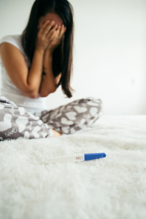 sad woman with pregnancy testの写真素材