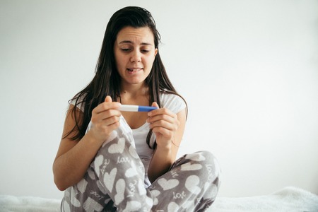 woman in bed surprised by pregnancy testの写真素材