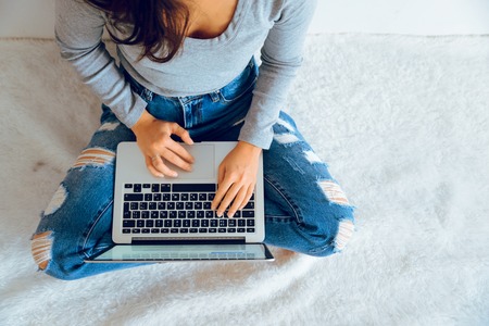 Top view of laptop in girls hands sitting on a floorの写真素材