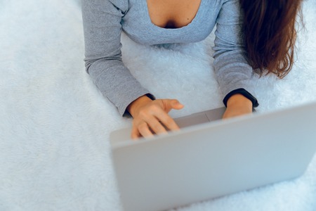 woman lying on fluffy carpet and working on laptopの写真素材