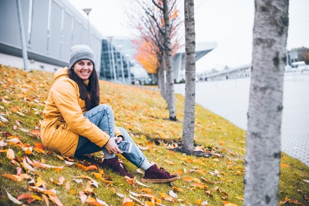 woman sitting on the ground under yellow treesの写真素材