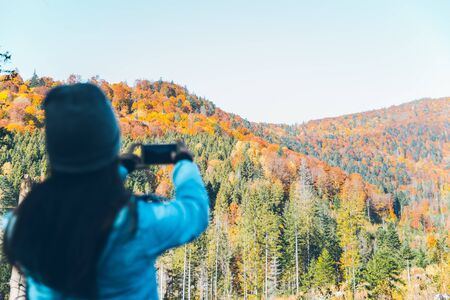 woman taking picture of the autumn carpathian mointains