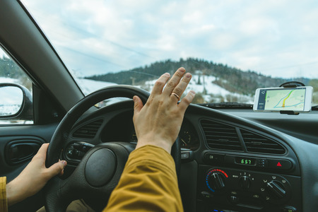 Driver's hands on a steering wheel and blurred road with navigation on mobile phoneの写真素材