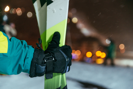 mans hand hold ski on the top of the snowed hill in evening timeの写真素材