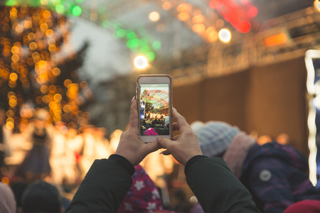 woman record concert on her phone while stand in crowdの写真素材
