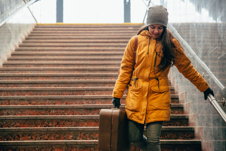 young woman with bags on stairs at railway stationの写真素材
