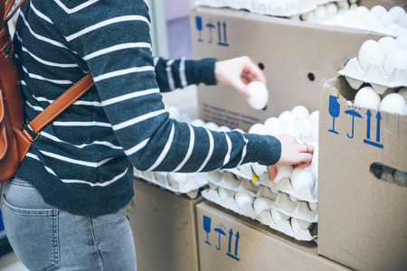 woman put solid eggs into egg tray in grocery storeの写真素材