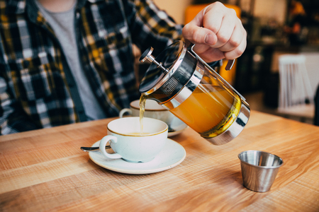 man fill up cup with hot tea from french pressの写真素材