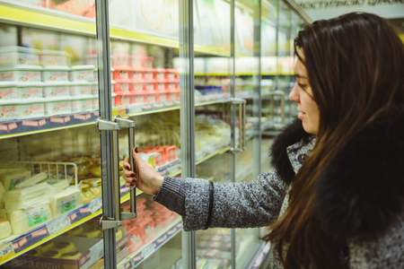 woman get cheese from the fridge in supermarketの写真素材