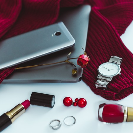 flat lay red sweater with different stuff on white backgroundの写真素材