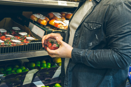 young man chose strawberry in the storeの写真素材