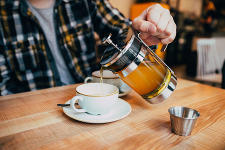man fill up cup with hot tea from french pressの写真素材