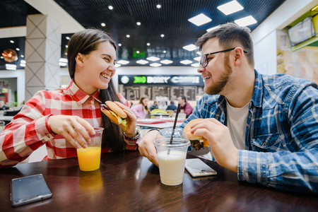 couple make pause for shopping eat burgers in mall cafeの写真素材