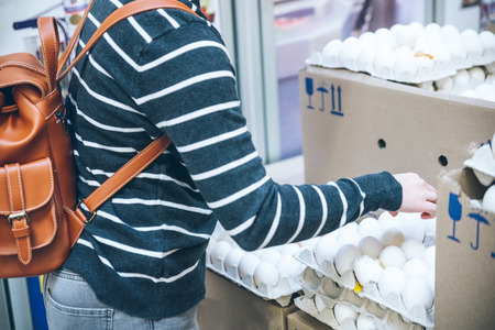 woman put solid eggs into egg tray in grocery storeの写真素材