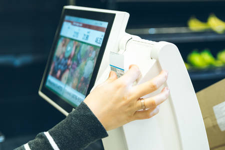 woman take sticker with price after weigh productsの写真素材