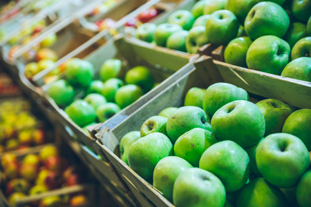 green apples in boxes on market shelves. grocery shopping concept. healthy food.の写真素材