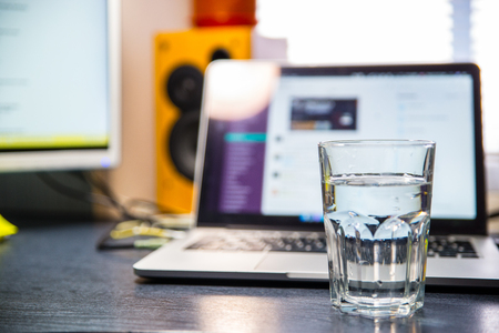 clean glass of water on table. laptop on backgroundの写真素材