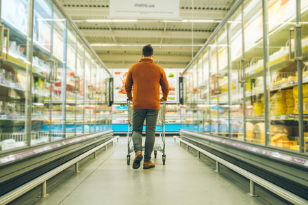 man walk with cart between rows with refrigerators. shopping conceptの写真素材