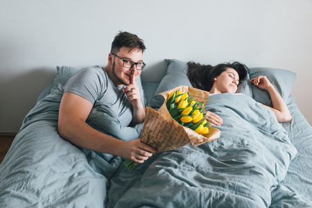 man bring flowers in bed. surprise for girlfriend in the morning. romantic conceptの写真素材