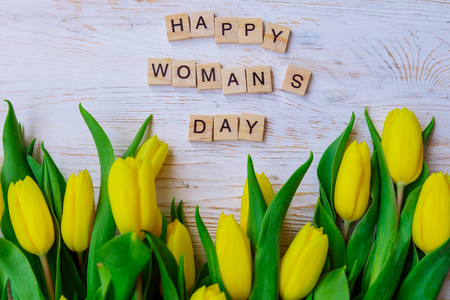 happy woman's day text. tulips overhead on white wooden backgroundの写真素材