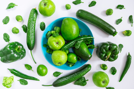green vegetables and fruits on blue plate on white background. overhead viewの写真素材