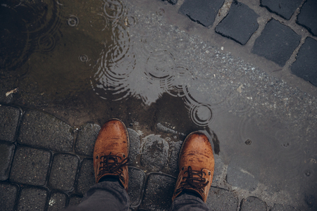 mans legs next to puddle. rainy weather.の写真素材