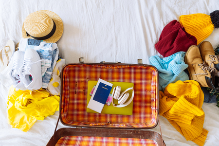 suitcase with winter and summer clothes on bed. preparing for trip. suitcase with garment. travel conceptの写真素材