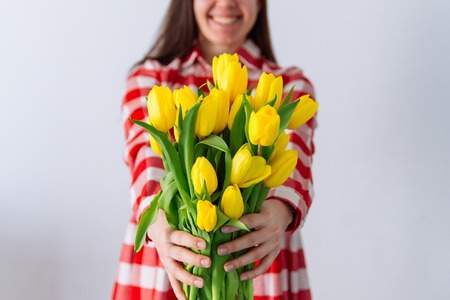 woman hold bouquet of yellow tulips. cover face with flowers. spring romantic conceptの写真素材