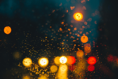 blurred car light trough wet glass. wet drops on glass.の写真素材
