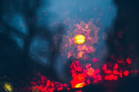 blurred car light trough wet glass. wet drops on glass.