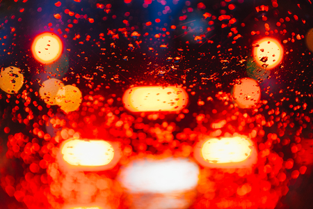 blurred car light trough wet glass. wet drops on glass.の写真素材
