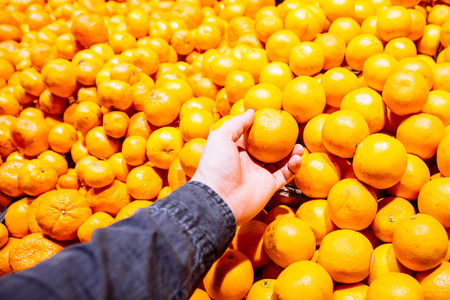 first-person view. man takes orange in store. grocery shopping concept