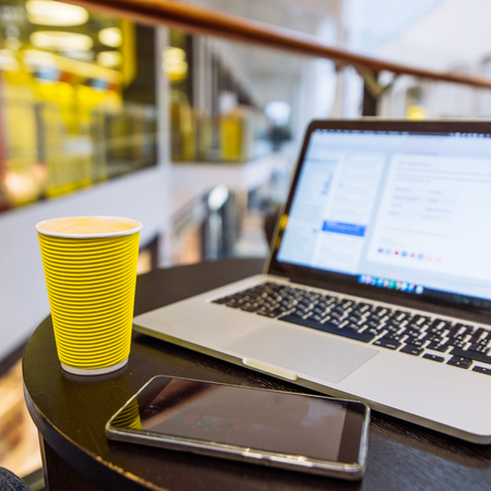 yellow coffee cup on table. laptop with cellphone on background. freelancer conceptの写真素材