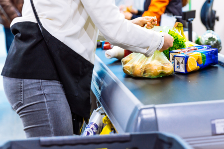 woman put products on the line near cashbox. grocery shopping conceptの写真素材