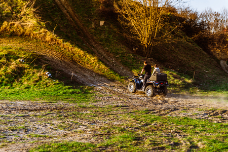 couple enjoys riding an ATV on forest hillsの写真素材