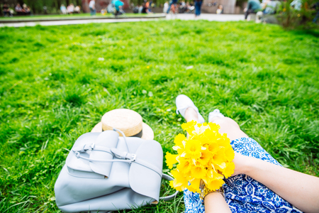 woman sitting on grass in city park with yellow flowersの写真素材