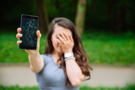 young sad adult woman showing cracked phone