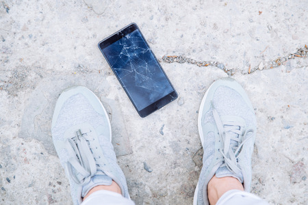 phone with cracked screen on ground. overhead viewの写真素材