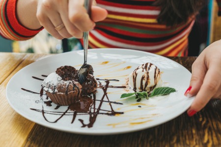 young adult woman eating chocolate fondant in cafe.の写真素材