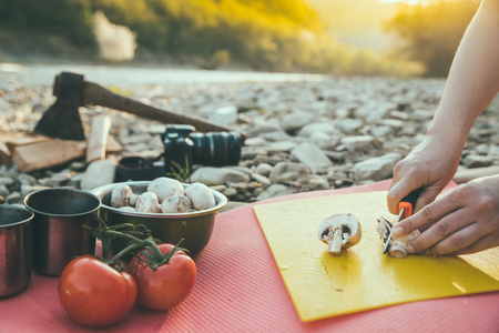 woman cooking on camp fire. wild nature resting. cutting mushroomsの写真素材